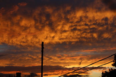 Low angle view of silhouette street light against dramatic sky