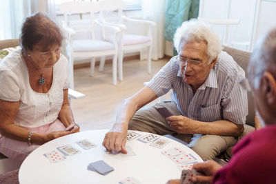 Senior people playing cards at table in retirement home