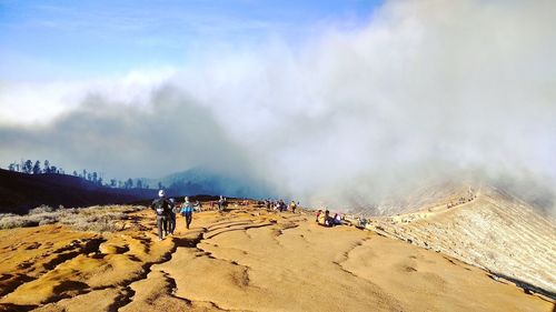 People working on mountain against sky