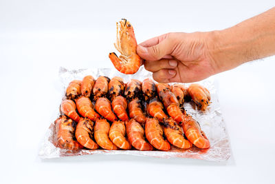 Close-up of hand holding burger against white background