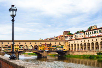 Arch bridge over river against sky in city