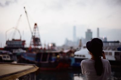 Rear view of woman by moored boats at harbor
