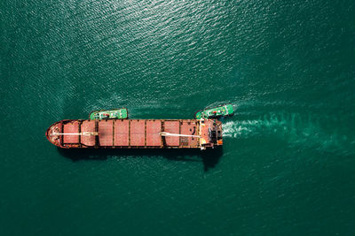 Aerial top view tugboat pulling red oil ship to shipyard dry dock repairing and maintenance in sea