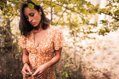 Close up of young woman looking down while standing in forest