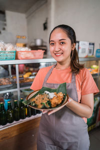 Portrait of smiling young woman eating food on table