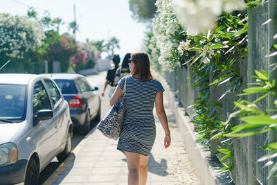 Rear view of woman walking on footpath by plants