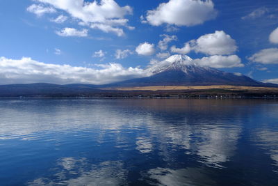 Mt fuji by lake against cloudy sky