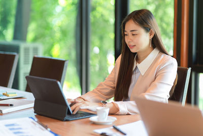 Young woman using phone while sitting on table