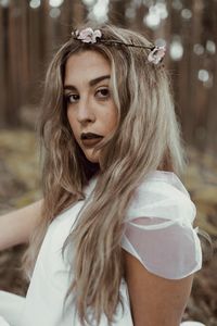 Portrait of beautiful young woman sitting in forest