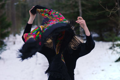 Woman removing scarf while standing on snow covered field