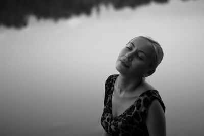 Young woman with eyes closed standing by lake