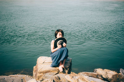 Woman sitting on rock by lake