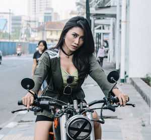 Portrait of woman sitting on motorcycle in city