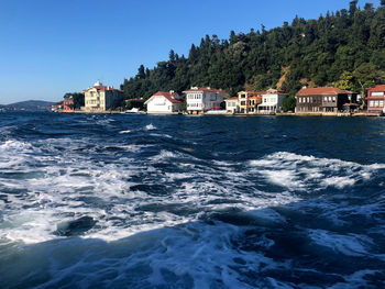 Scenic view of sea and buildings against clear blue sky