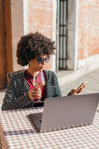 Freelancer young woman using smartphone and drinking a wine