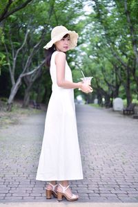 Woman wearing hat standing on footpath