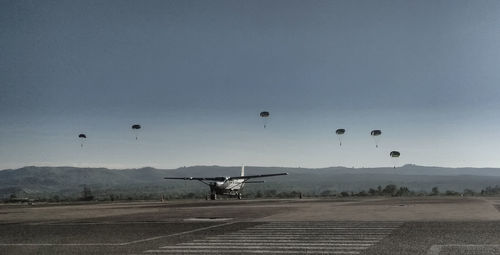 Airplane flying over airport runway against sky