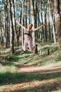 Full length of woman jumping in forest