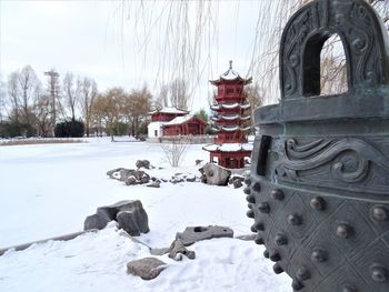 Snow covered land by buildings against sky during winter