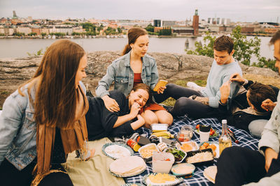 Male and female friends enjoying food on picnic blanket