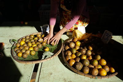 Midsection of person selling oranges in market