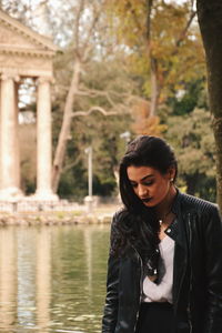 Thoughtful young woman standing by pond