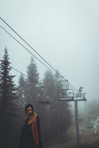 Woman standing by tree against sky during winter