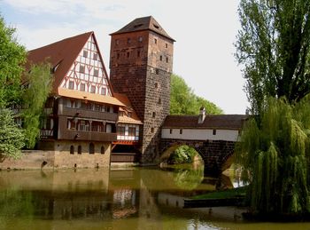 Buildings by river against sky