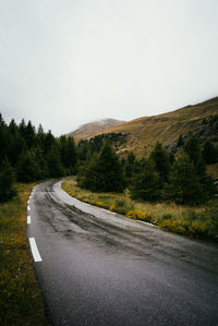 Empty road amidst trees against clear sky