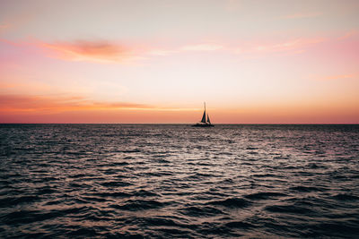 Sailboat sailing on sea against sky during sunset