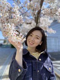 Portrait of smiling young woman with cherry blossom