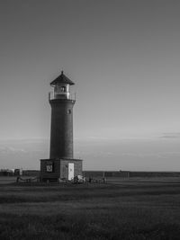 Lighthouse on field against sky