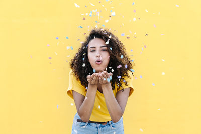 Portrait of happy girl standing against yellow background