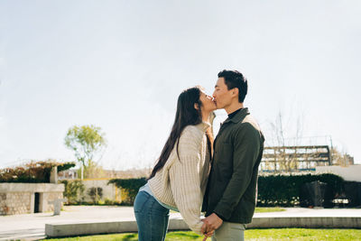 Side view of couple standing against sky