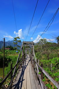 Footbridge amidst trees against sky