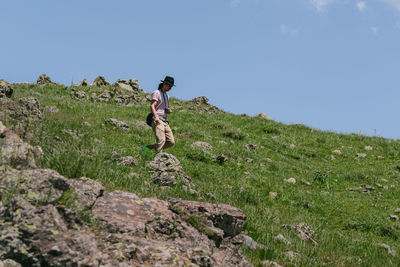 Full length of man climbing on field against sky