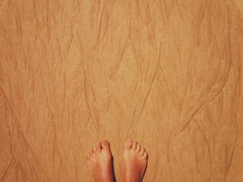 Low section of woman standing on sand