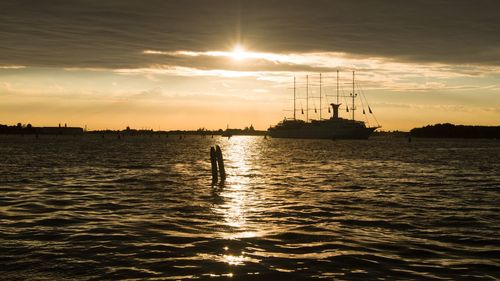 Silhouette sailboats in sea against sky during sunset