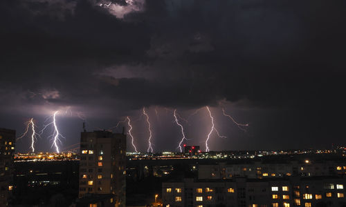 Lightning over illuminated buildings in city at night
