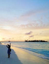 Man standing on beach against sky during sunset