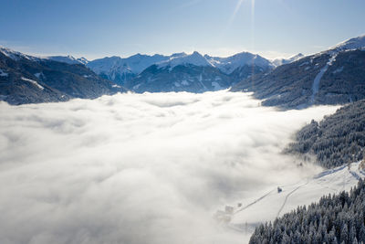 Aerial view of clouds amidst snowcapped mountains against sky