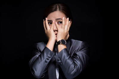 Scared businesswoman looking away against black background