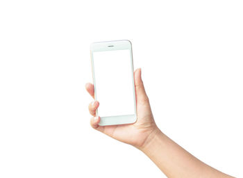 Cropped hand of person holding smart phone with blank screen against white background
