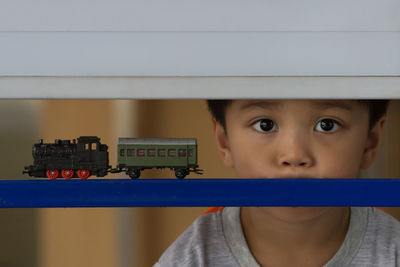 Close-up portrait of boy looking through railing