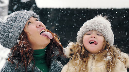 Catch snowflakes with tongue. happy , mother and daughter are catching snowflakes with their tongues