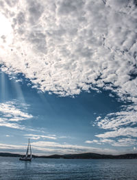 Boat sailing in sea against cloudy sky