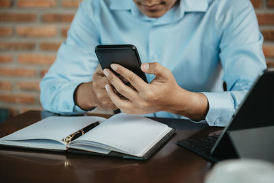 Midsection of man using digital tablet at table