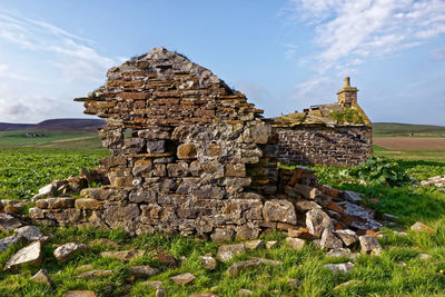 Stone structure on field against sky