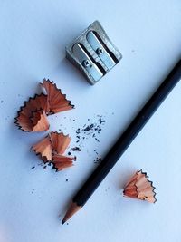 High angle view of pencil with shavings and sharpener on white background