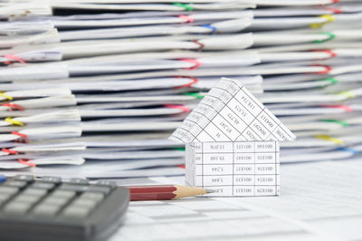 Close-up of model house with calculator and pencil on financial documents